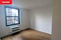 Empty room with hardwood flooring, a large window, and a wall-mounted air conditioning unit.
