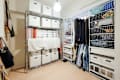 Organized closet space with white storage boxes, hanging clothes, and wire shelves filled with folded items.