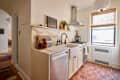 Compact kitchen featuring a marble backsplash, stainless steel appliances, and hexagonal terracotta tiles.