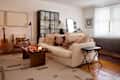 Cozy living space featuring a cream sofa with decorative pillows, wooden coffee table, guitar, and a glass display cabinet.