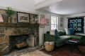 Cozy living room featuring a green sectional sofa, stone fireplace, and colorful quilt wall hanging.