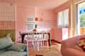 Bright kitchen with pink cabinetry, white dining table, and a cozy green sofa in the foreground.