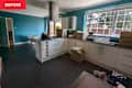 Modern kitchen with teal walls, white cabinets, a gas stove, and unpacked boxes scattered on the floor.