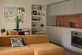 Cozy living space featuring a brown sectional sofa with a zebra print pillow, a round dining table, and modern kitchen cabinetry.