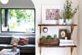 Wooden shelves with potted plants, framed art, books, and a vintage crate in a living room with a gray sofa and colorful cushions.