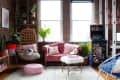 Cozy living room with pink sofa, hanging chair, arcade machine, plants, and fluffy decor.