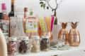Bar setup with assorted liquor bottles, glass jars of dried herbs, colorful straws, and copper pineapple cups.