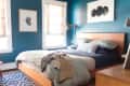 Teal bedroom with wooden bed, layered bedding, abstract wall art, and patterned rug.