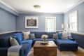 Blue living room with a large sectional sofa, wooden coffee table, and a camera print on the wall.