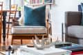 Living room with a glass coffee table, bookshelves, blue pillow on a chair, and a gray sofa.