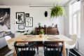 Dining room with wooden table, black and white chairs, hanging plant, wall art, and a piano with decor items.