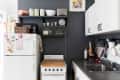 Small kitchen with white cabinets, dark countertops, a vintage stove, and a fridge decorated with magnets.