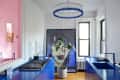 Modern kitchen with blue cabinets, abstract art, potted plant, and circular blue chandelier.