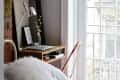 Cozy bedroom with a brick wall, desk with laptop, books, and decor, next to a large window with white trim.