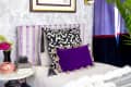 A bedroom with purple wallpaper, purple curtains, and a purple striped headboard