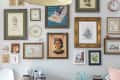 Gallery wall with diverse framed art, including portraits, landscapes, and botanical prints, above a kitchen counter.