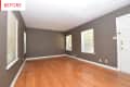Empty room with gray walls, wooden floor, three windows, and a white door.