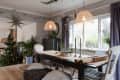 Dining room with a wooden table, pendant lights, Christmas tree, and star decorations by the window.