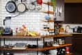 Kitchen with white subway tiles, wooden shelves, hanging pots, blender, and assorted kitchenware on countertops.