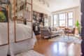 A light-filled living room with two white bookcases separating the sleeping area from the living space