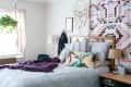 Cozy bedroom with patterned bedding, tropical pillows, a purple throw, hanging plant, and geometric wall art.
