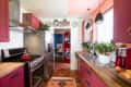 A galley kitchen with magenta cabinetry and Saltillo flooring
