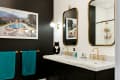 One black wall and an adjacent white wall in a modern bathroom with brass fixtures