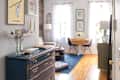 Cozy living room with a blue dresser, small round dining table, two chairs, and framed art on the walls.