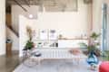 Modern living room with a white bench, plants, wall art, and a shelf with books and decor.