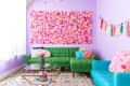 A very colorful living room has a geometrically shaped coffee table with a glass top.