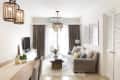 Living room with beige sofa, wooden coffee table, TV, and pendant lights, featuring large windows and framed wall art.
