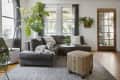 Gray sectional sofa with a dog, potted plants, and a patterned ottoman in a bright living room with wooden door.