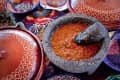 Molcajete with red salsa surrounded by colorful Mexican pottery dishes.