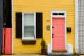 Yellow house facade with pink door, shutters, and address number
