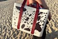 Someone toting Owala collapsable bag on beach.