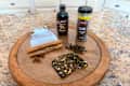 A wooden serving tray with cinnamon sticks, cloves, a small pouch, and a bottle of extract.