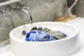 Clothes soaking in a white bathroom sink with a chrome faucet.