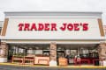 Trader Joe's storefront with red signage, stone accents, and outdoor produce display.