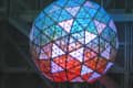 Colorful illuminated geodesic sphere with triangular panels, resembling a New Year's Eve ball.