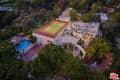 Aerial view of a luxury estate with a tennis court, pool, and lush greenery surrounding the property.