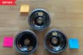 Three dirty stove burner drip pans on a wooden surface, labeled 1, 2, and 3 with sticky notes.