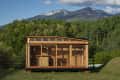 Wooden cabin with large windows set against a backdrop of lush green trees and distant mountains.