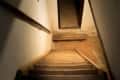 Dimly lit staircase leading to a basement with a wooden bench at the bottom.