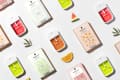 Colorful Touchland hand sanitizers and packaging with fruit slices and leaves on a light surface.