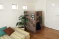 Small bedroom with a striped bed, potted plant, and a wooden divider featuring wall art, headphones, and storage pockets.