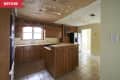 Dated kitchen with wooden cabinets, peeling ceiling, tiled floor, and a white refrigerator.