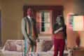 Man and woman in vintage living room with floral sofa, lamps, and curtains, displaying a glitch effect.