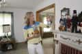 Woman in striped shirt holding a football-themed figurine in a room with collectible dolls on a mantel.
