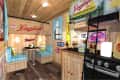 Wood-paneled room with Leinenkugel's decor, blue checkered booth seating, and bottles on a black counter.