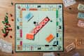 Monopoly board game setup with cards, dice, and money on a wooden table.